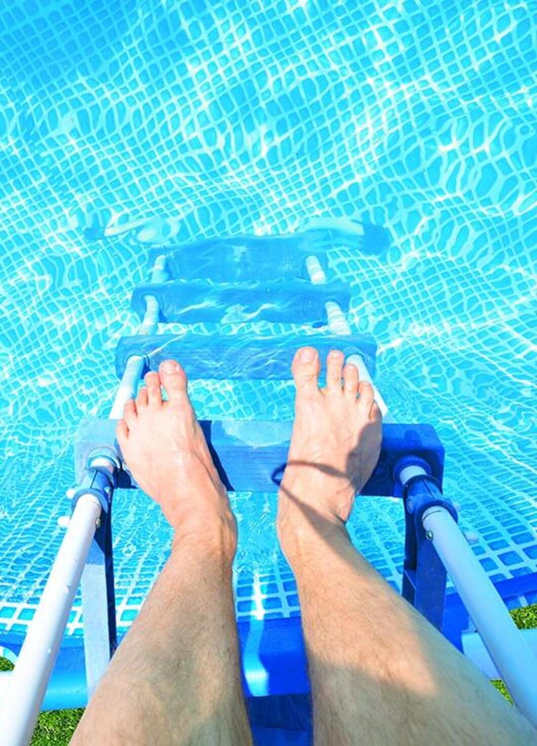 Blick auf Füße einer Person über dem eingang zu einem Pool.
